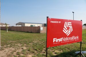 A sign standing on an open lot reads, "Financed by First National Bank."