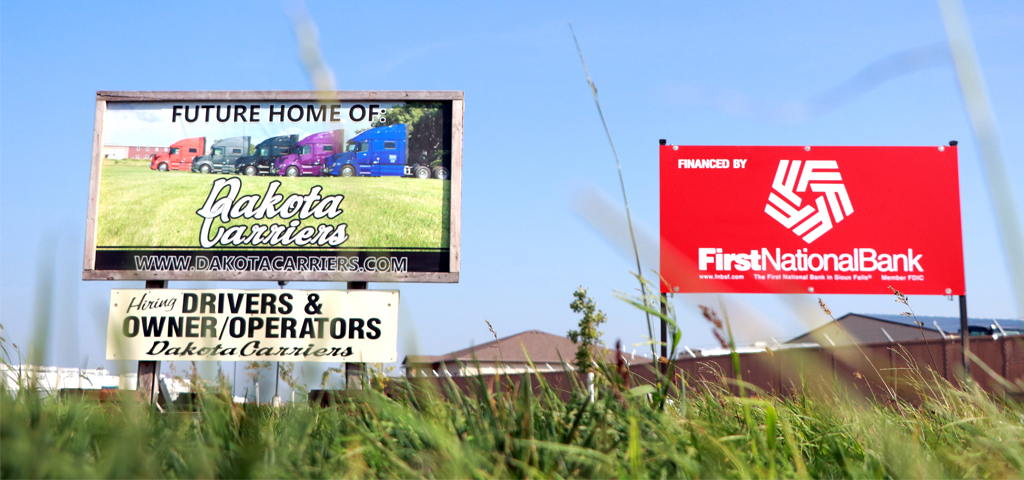 Signs for First National Bank and trucking company Dakota Carriers stand side by side in Sioux Falls.