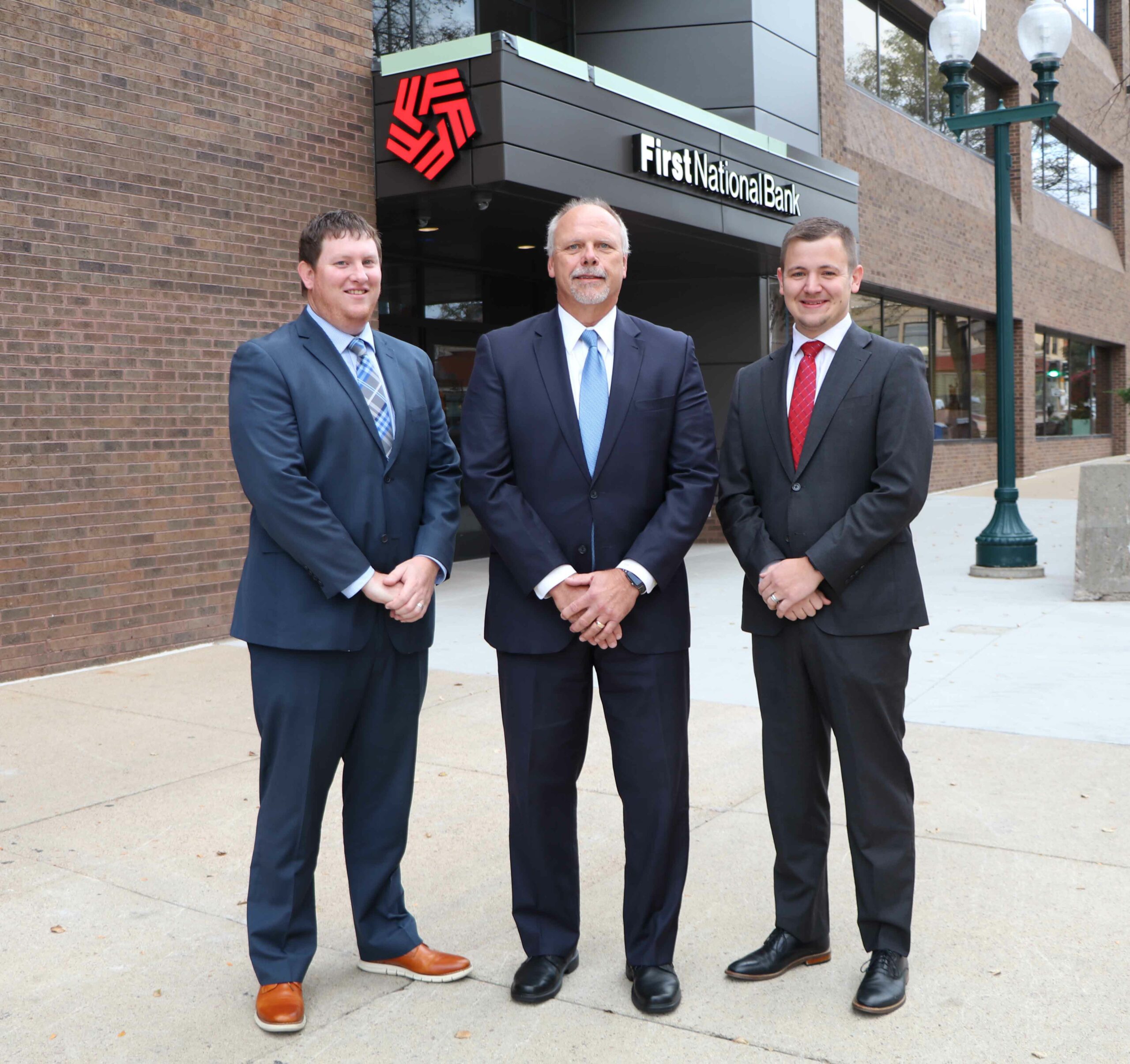 Business Bankers Derek Simonsen, Russ Robers, and Justin Zandstra pose for a team picture in front of First National Bank.