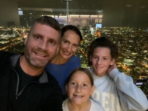 Adam Cox posing for a selfie with his wife and two daughters.
