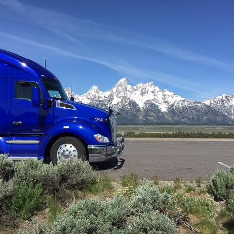 A truck from Doug Newman's business, Newman Trucking, parked on a road with a snowy mountain in the background.