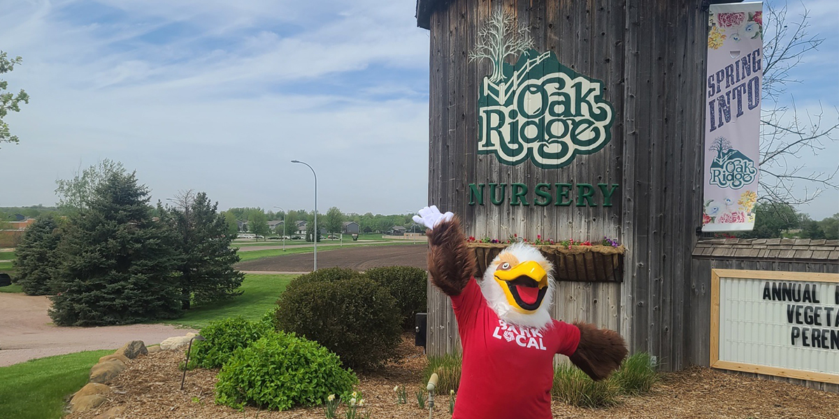 Eagle mascot poses in front of wooden silo at Oakridge Nursery in Brandon, SD.