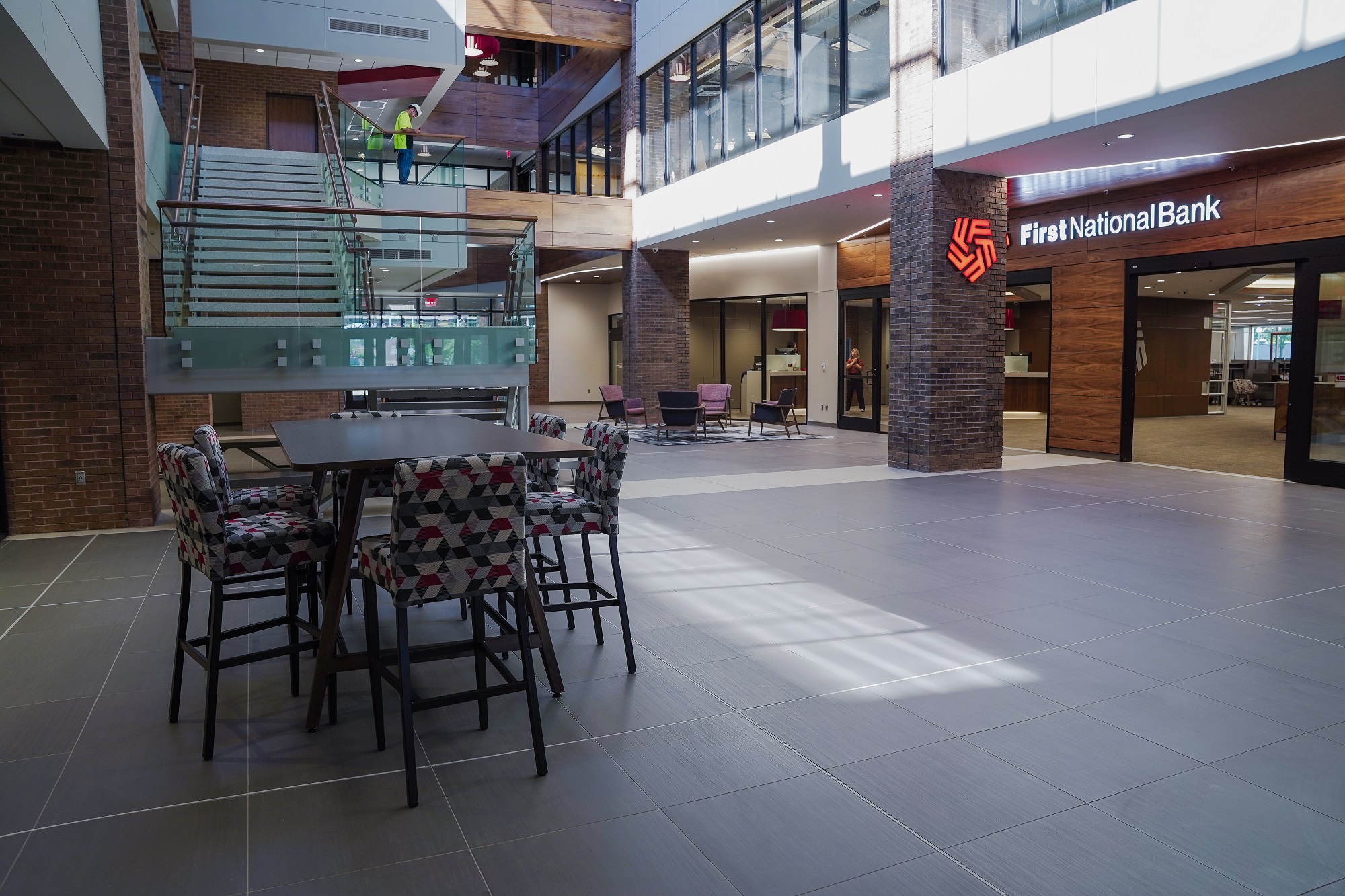 A wide-angle image of First National Bank's renovated atrium portrays new furniture, signs, and a staircase.