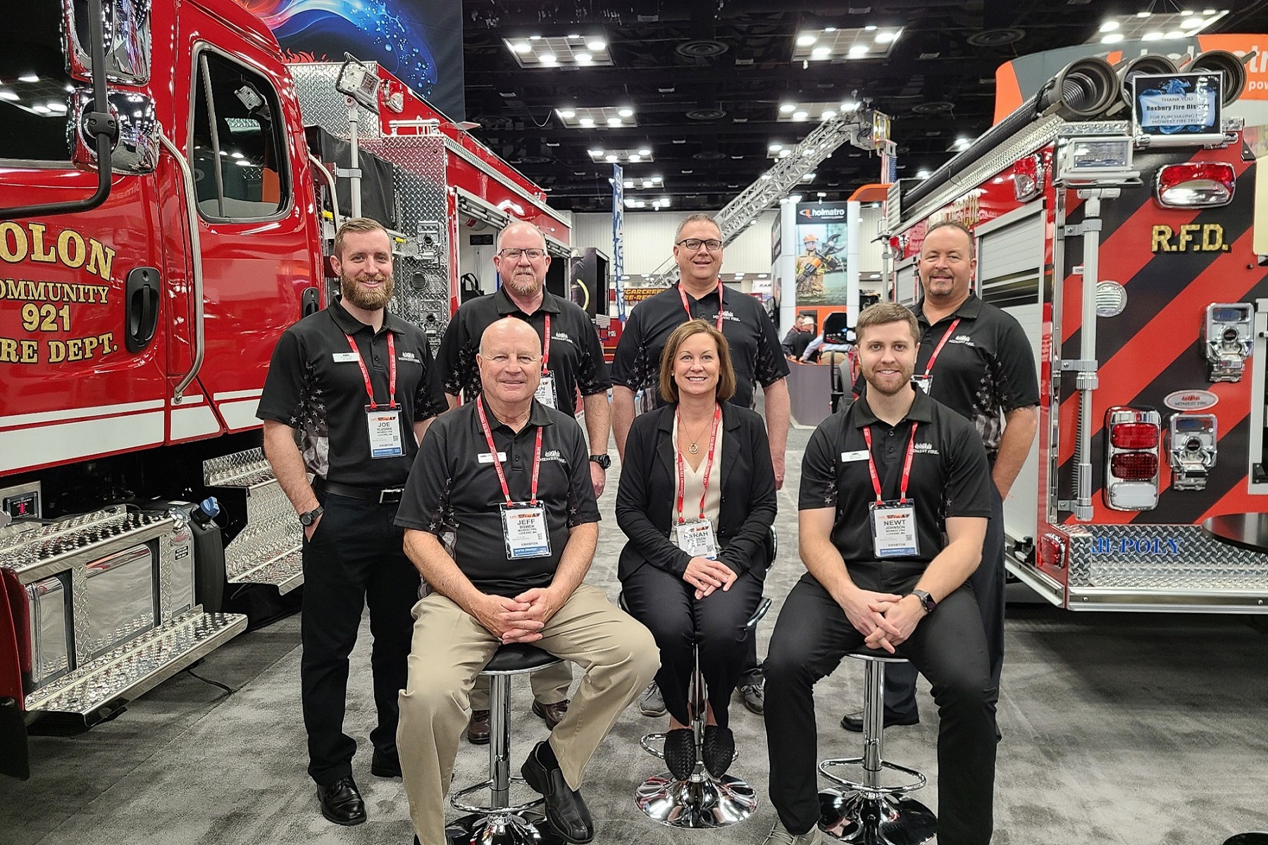 Sarah Atchison and her manufacturing team posing in front of their firetrucks.