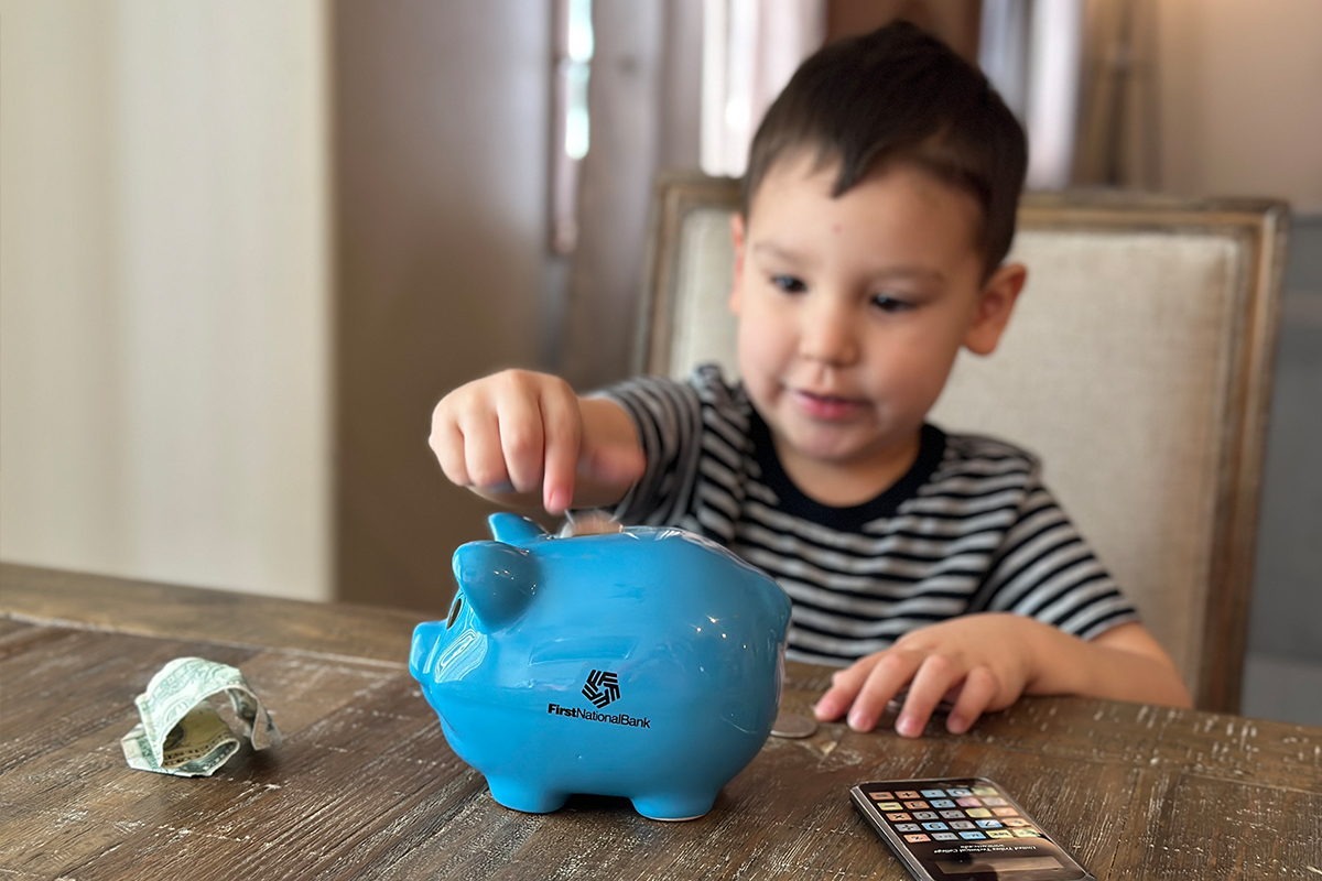 A young boy putting coins into a piggy bank