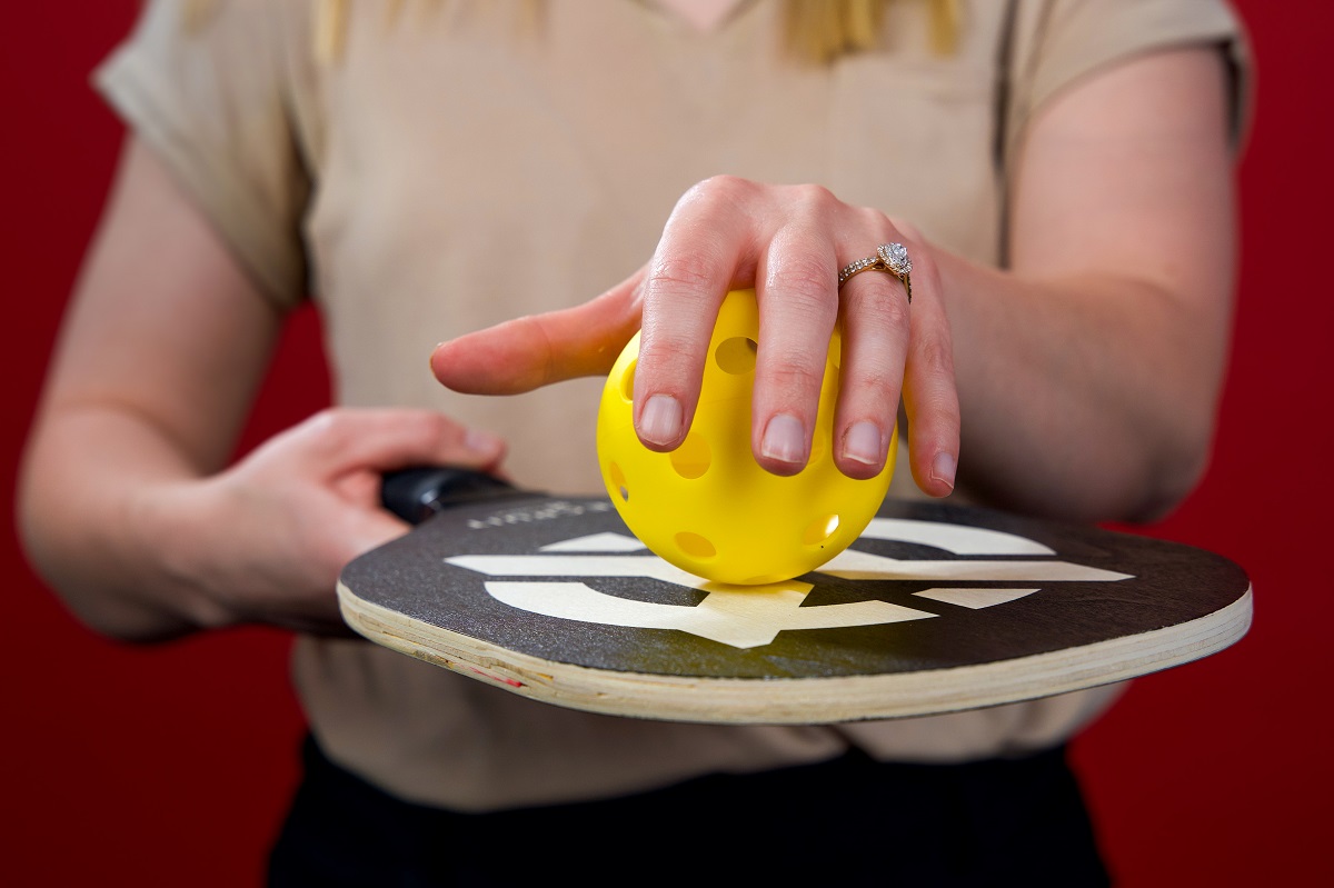 A close up of Jacquelyn Benda holding a pickleball and a racket.