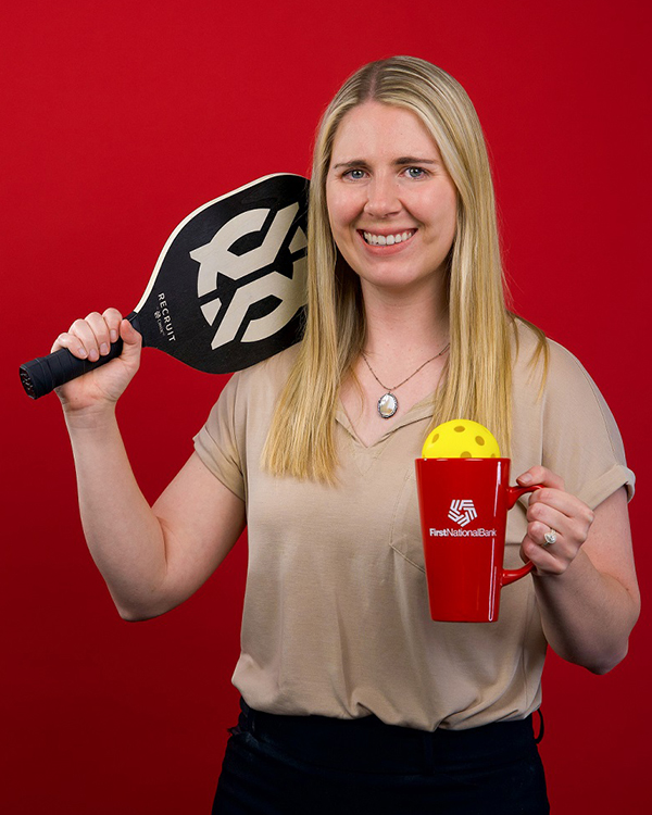 Digital Strategist Jacquelyn Benda poses with a mug and pickleball racket.