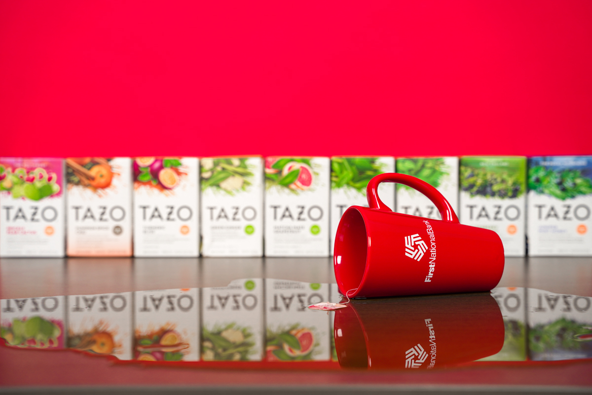 A mug of tea spilled over a table, with boxes of different tea flavors in the background.