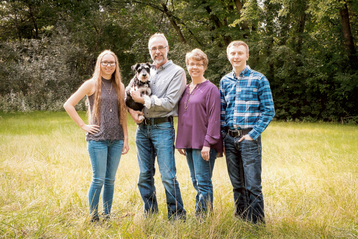 Lisa Hochhalter and her family pose for a family photo in a grassy field. 