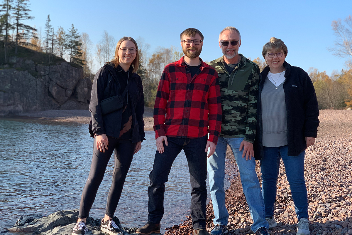 Lisa Hochhalter and her family pose for a picture near a body of water at the bottom of a rocky cliff. 