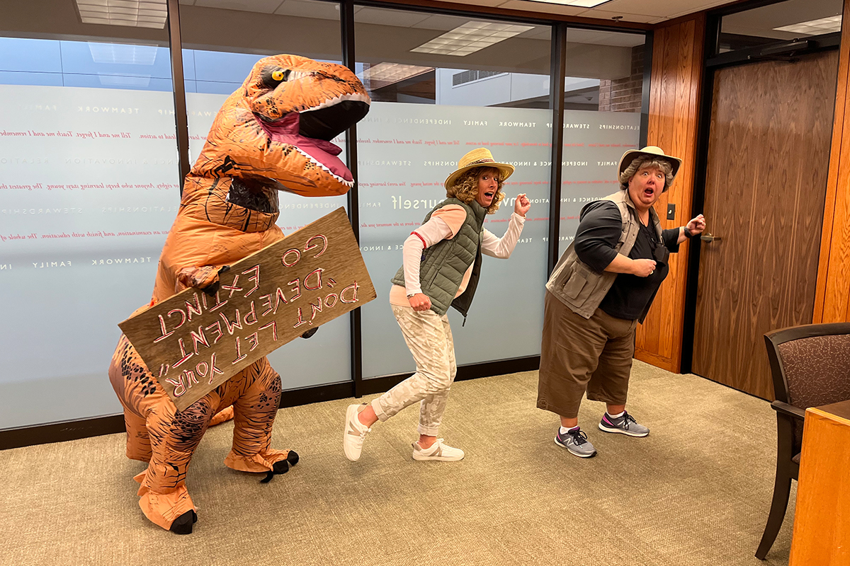 Members of the FNB Employee Development team pose as Jurassic Park characters with a sign that reads, "Don't let your 'development' go extinct."