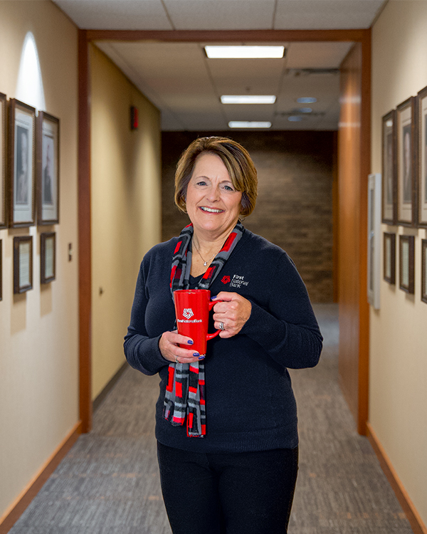 Deb Thompson holds a mug of tea while standing in First National Bank's Hall of Presidents.