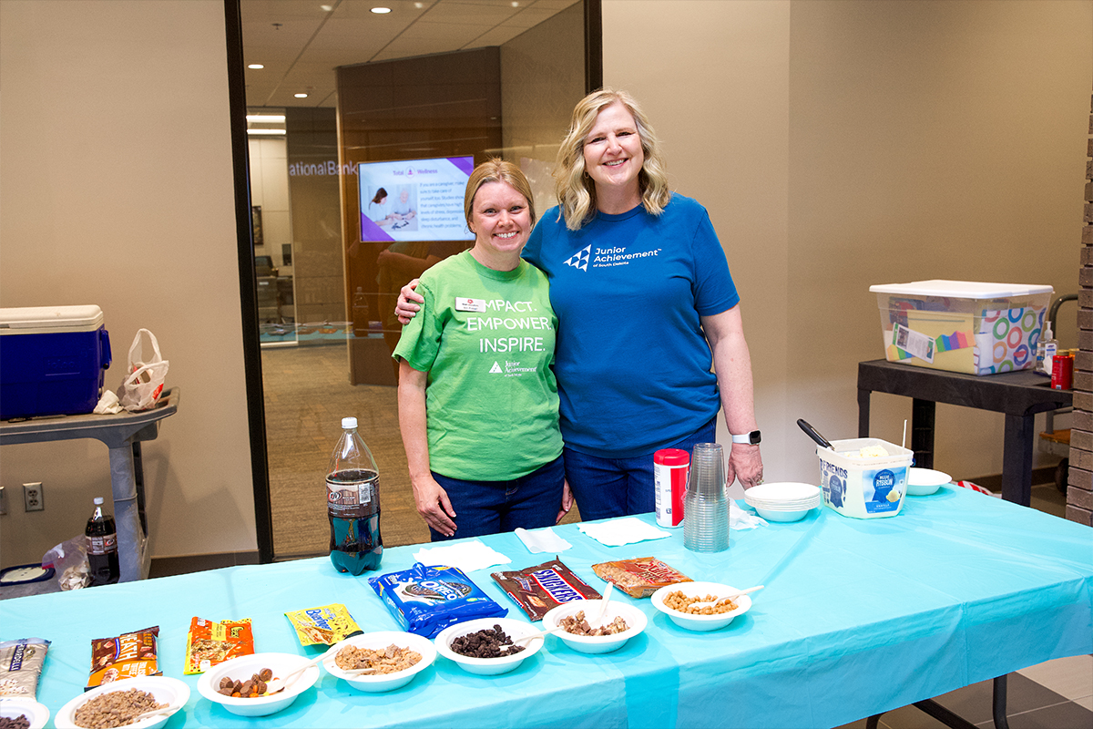 Two First National Bank employees hosting the annual Junior Achievement ice cream social.