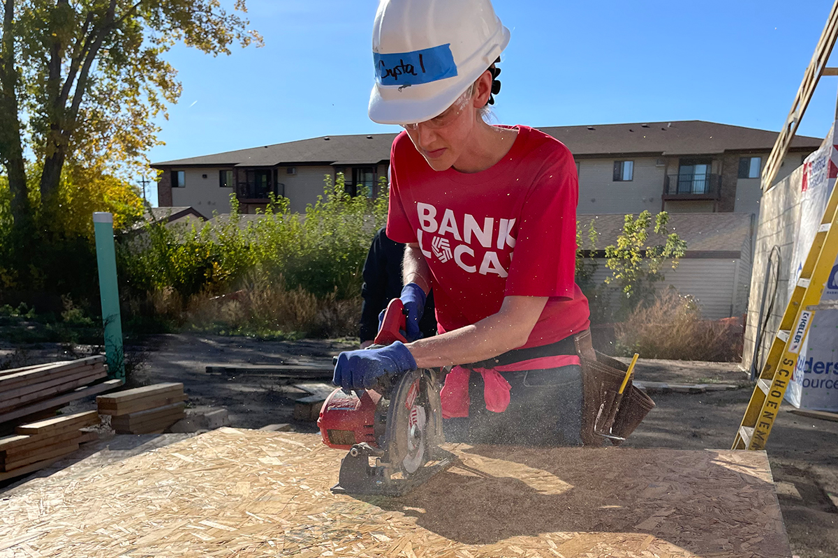 A First National Bank employee sawing wood at the Veterans Community Project in Sioux Falls.