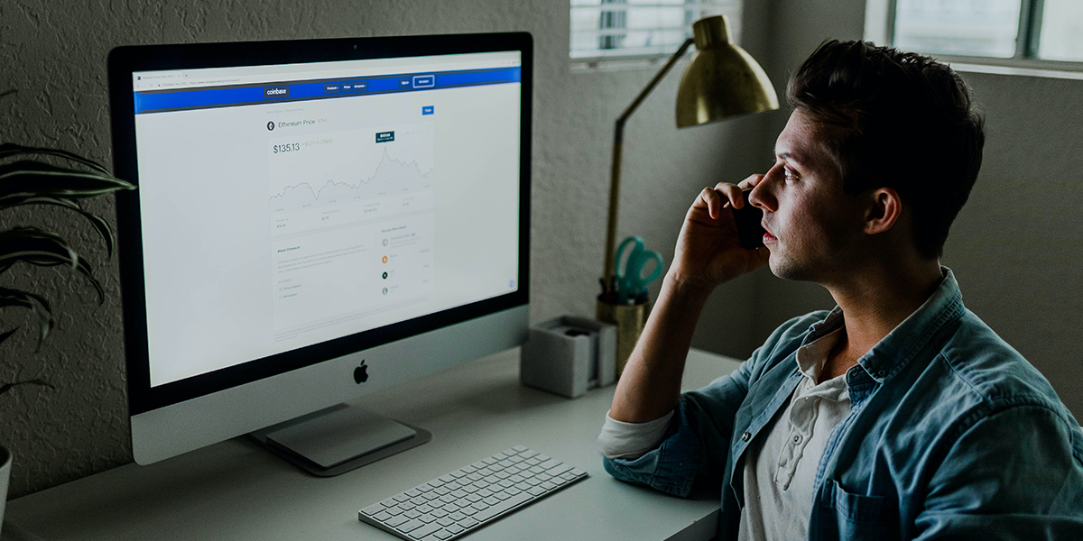 A man at a desk checking his investment accounts on the computer.