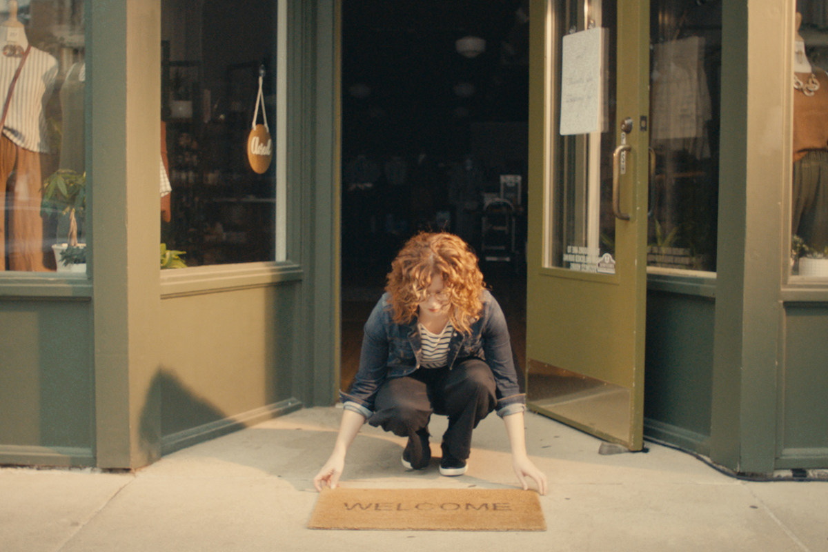 Sara Jamison laying a welcome mat in front of her Sioux Falls store, Terra Shepherd Boutique & Apothecary.