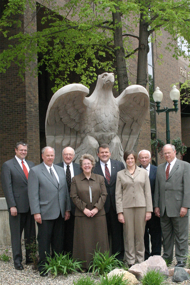 Family shareholders of First National Bank in front of an eagle statue. 