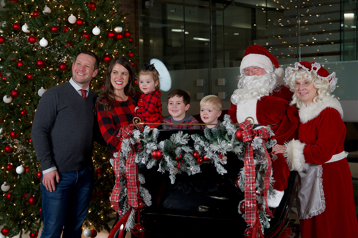 Maggie and Kyle Groteluschen pose for a picture with their three children and Santa and Mrs. Claus.