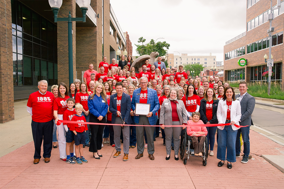 A large group of employees outside of First National Bank for a ribbon cutting.