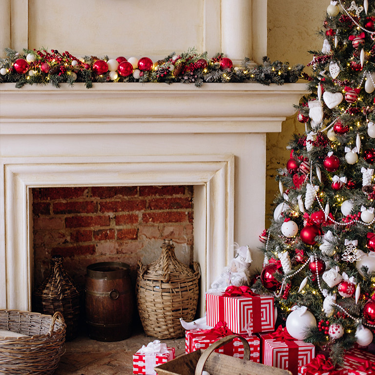 A Christmas tree in front of a fireplace.
