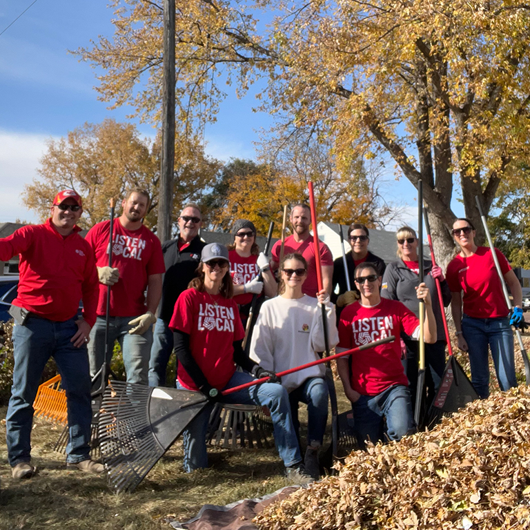 A group of First National Bank teammates raking leaves for Rake the Town.