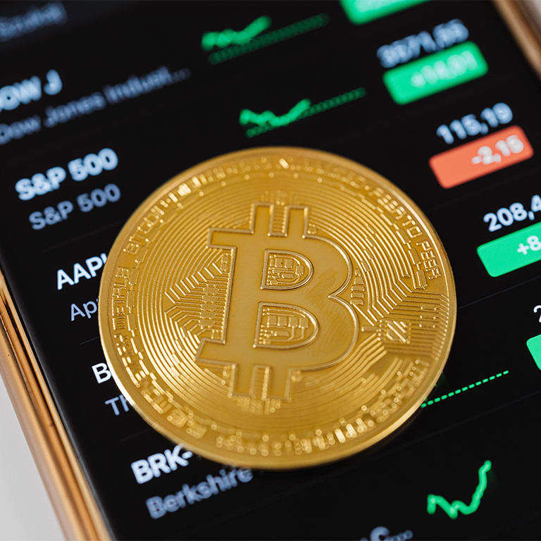 A bitcoin sitting on a smartphone screen.