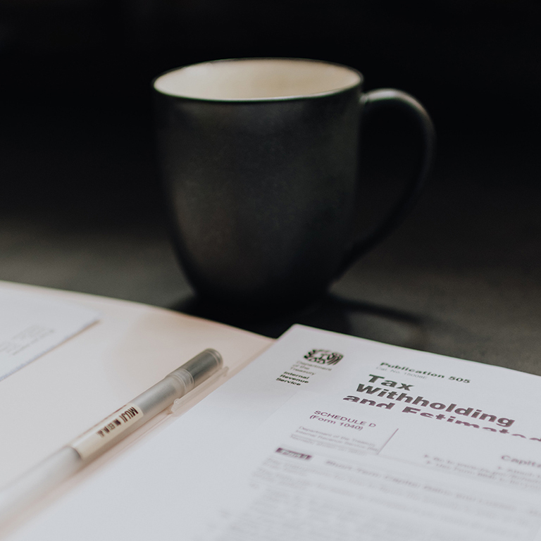 Paperwork and a coffee mug sitting on a table.