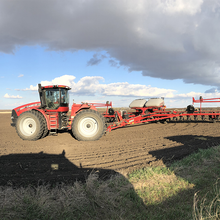 Tractor pulling a planter in a field.