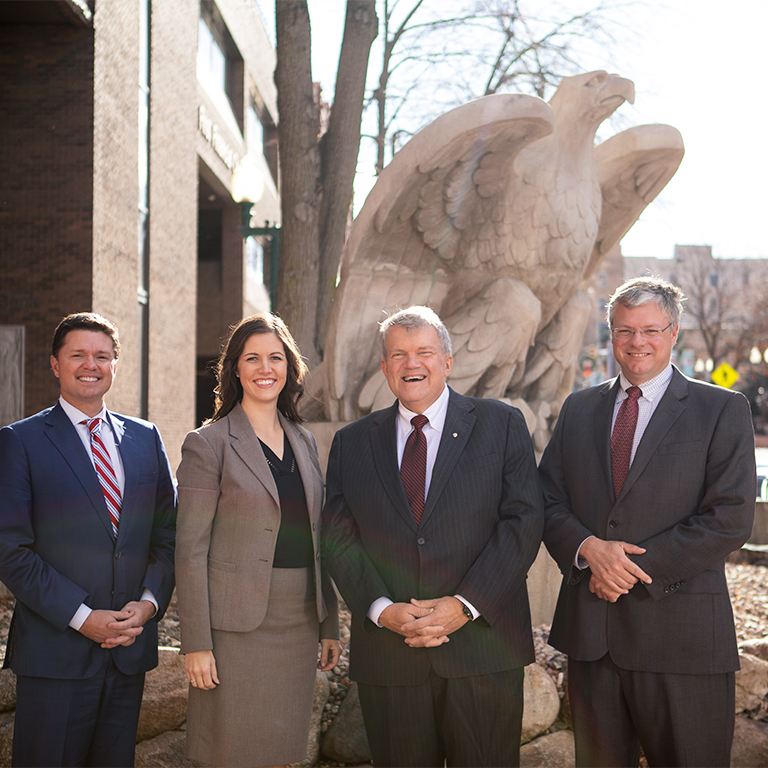 Chris Ekstrum, Maggie Groteluschen, Bill Baker, and Bob Baker standing outside The First National Bank in Sioux Falls.
