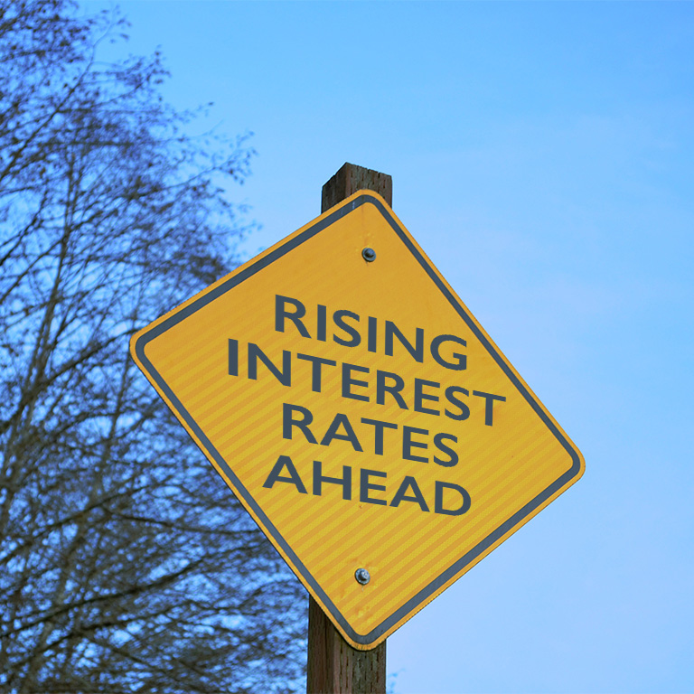 A yellow street sign that says "rising interest rate impacts."