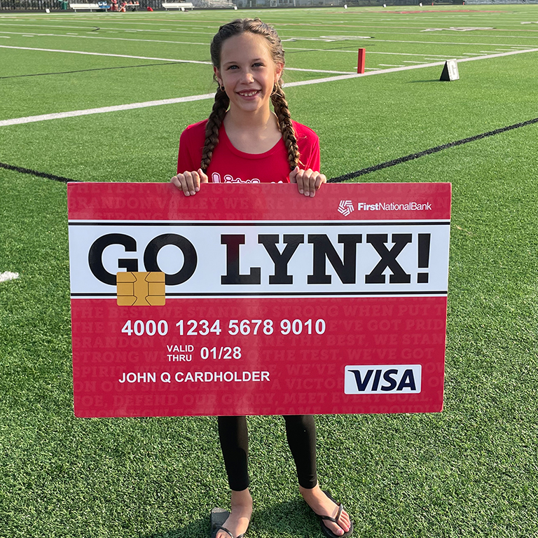 Young girl holding a Brandon Valley Community Card from First National Bank.