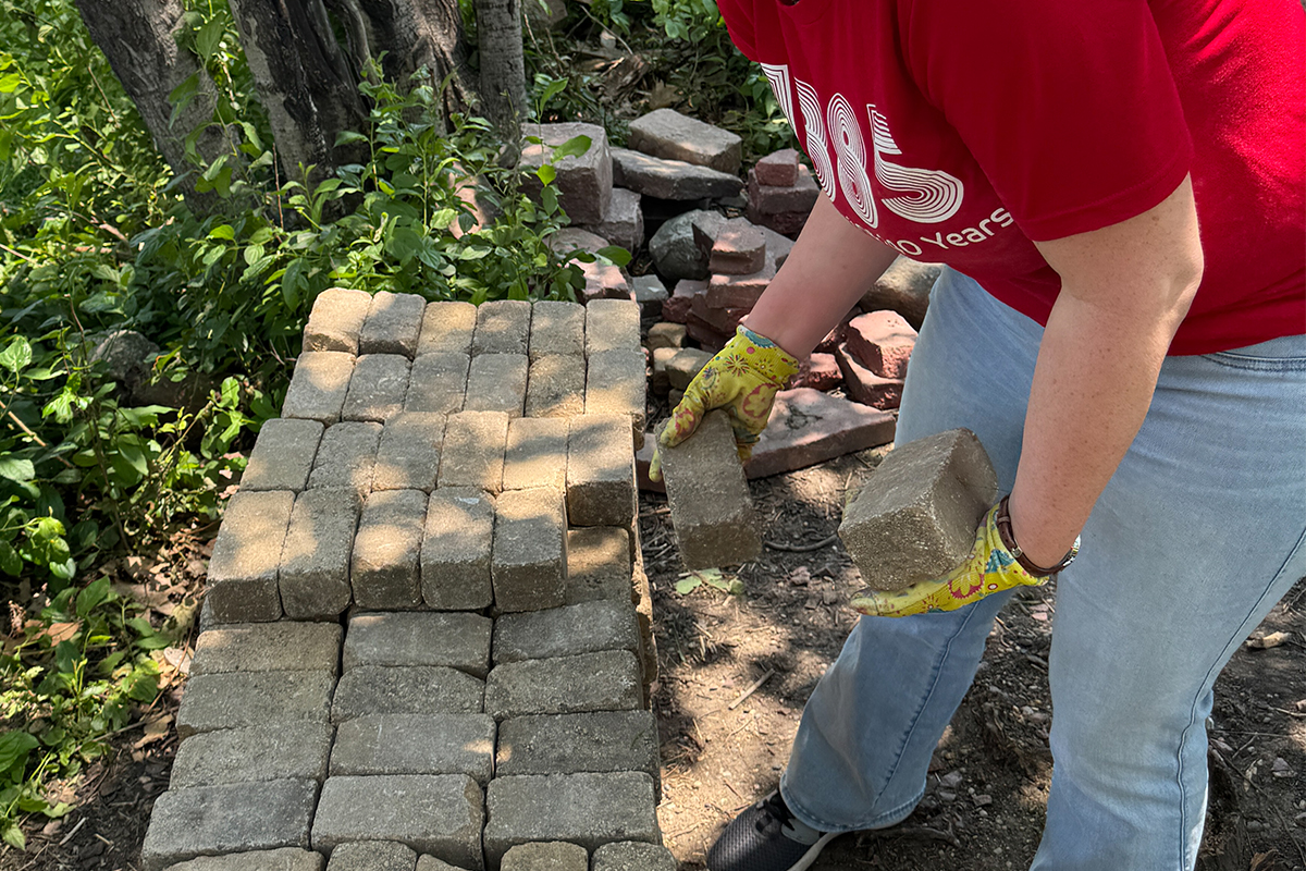 A volunteer stacking paving stones.