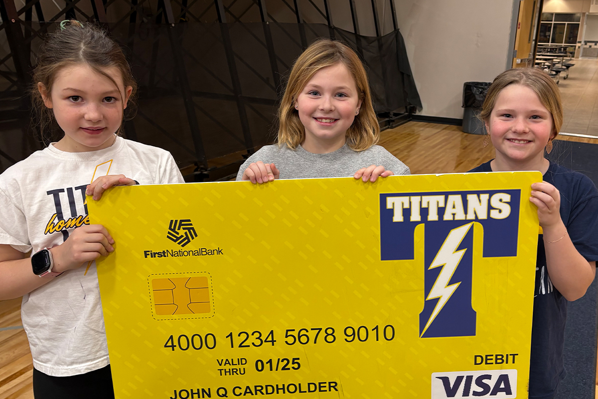 Three young girls holding a Tea Community Card.