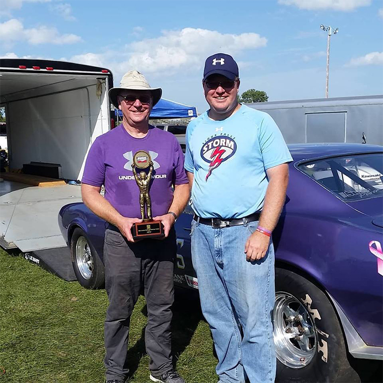 Adam Lamprecht with his dad holding a drag racing trophy.