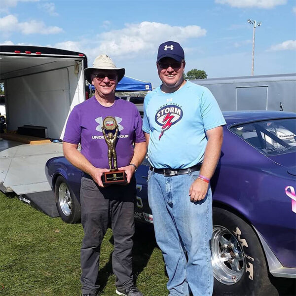 Adam Lamprecht with his dad holding a drag racing trophy.