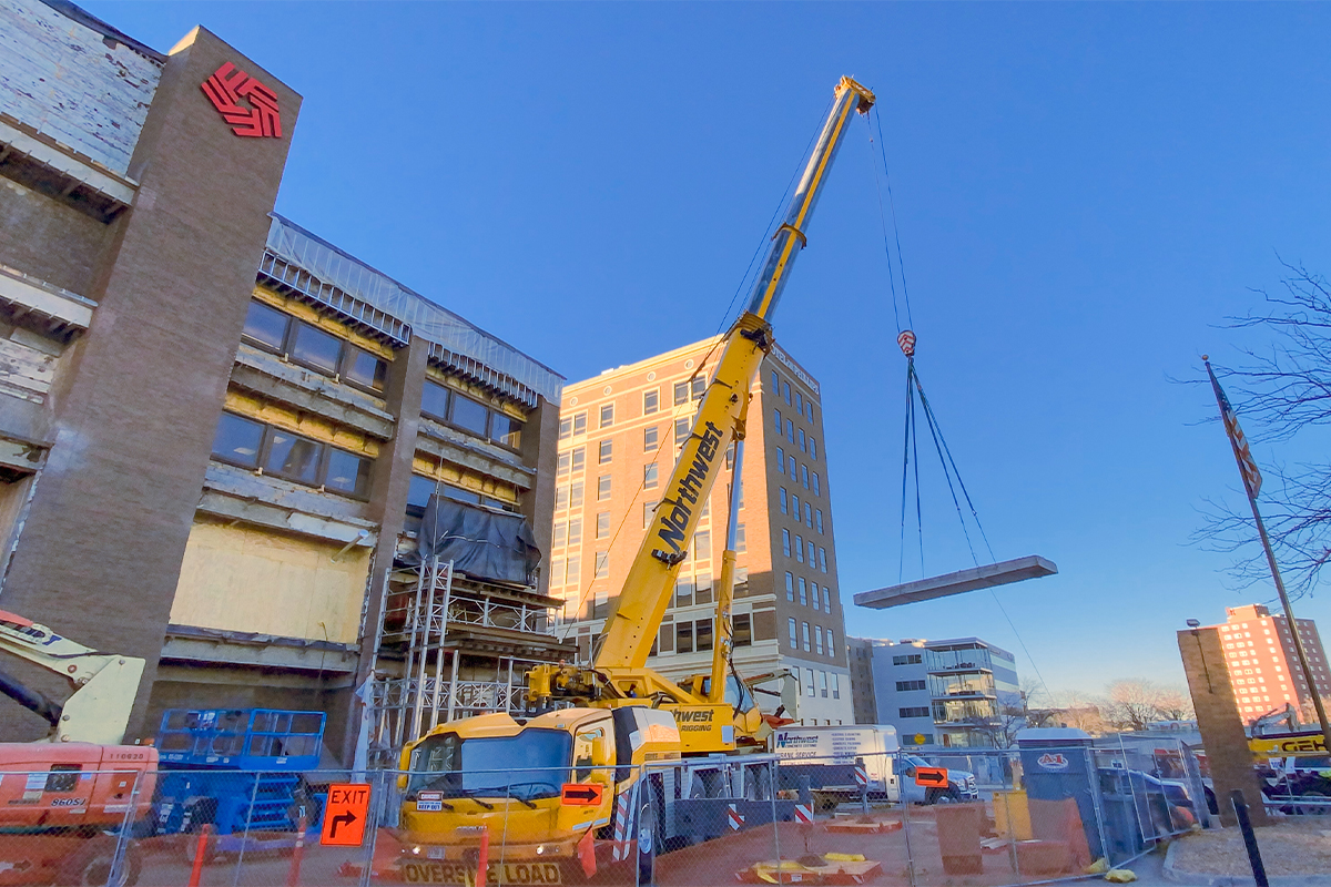 A crane removing a concrete slab from a building.