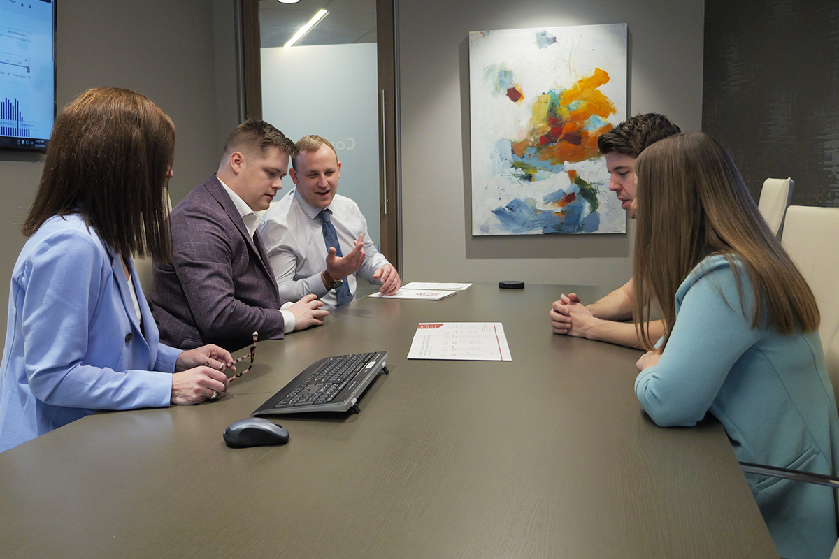 A group of financial advisors meeting with a client in a conference room.