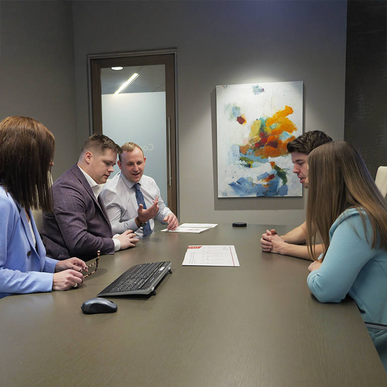 A group of financial advisors meeting with a client in a conference room.