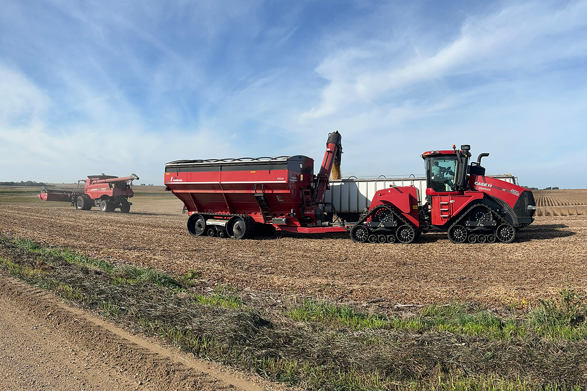 A tractor and grain cart in the field during corn harvest.