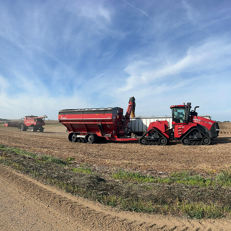 A tractor and grain cart in the field during corn harvest.