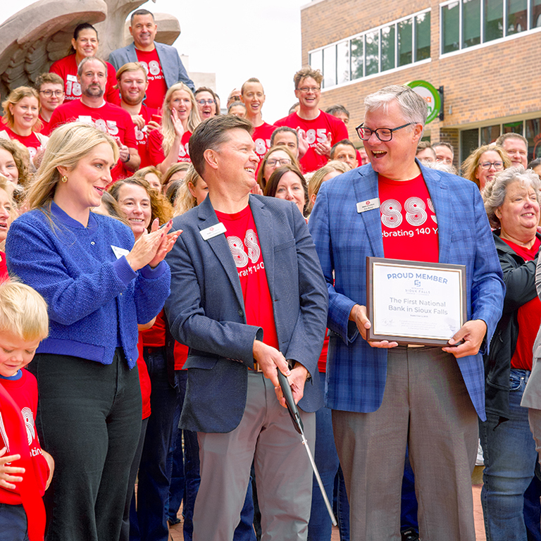 First National Bank employees cut a ribbon for the bank's 140th anniversary.