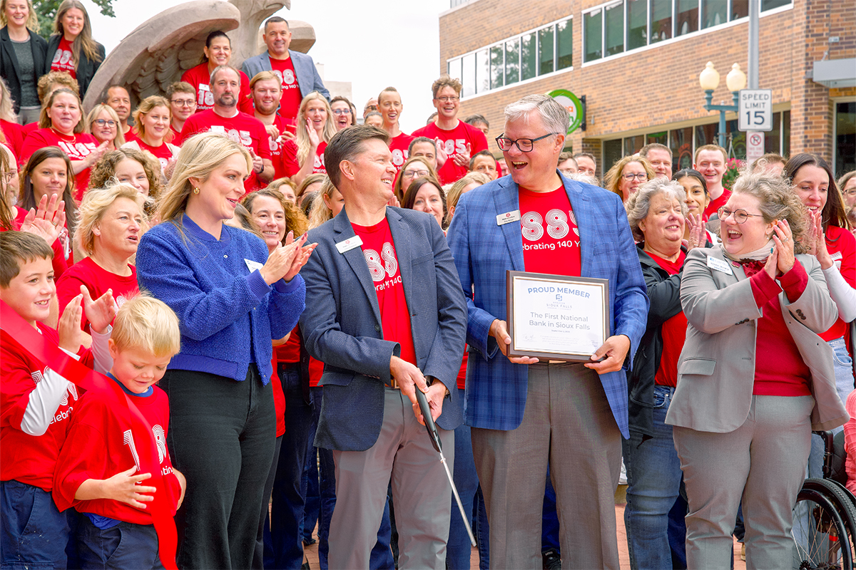 First National Bank employees cut a ribbon for the bank's 140th anniversary.