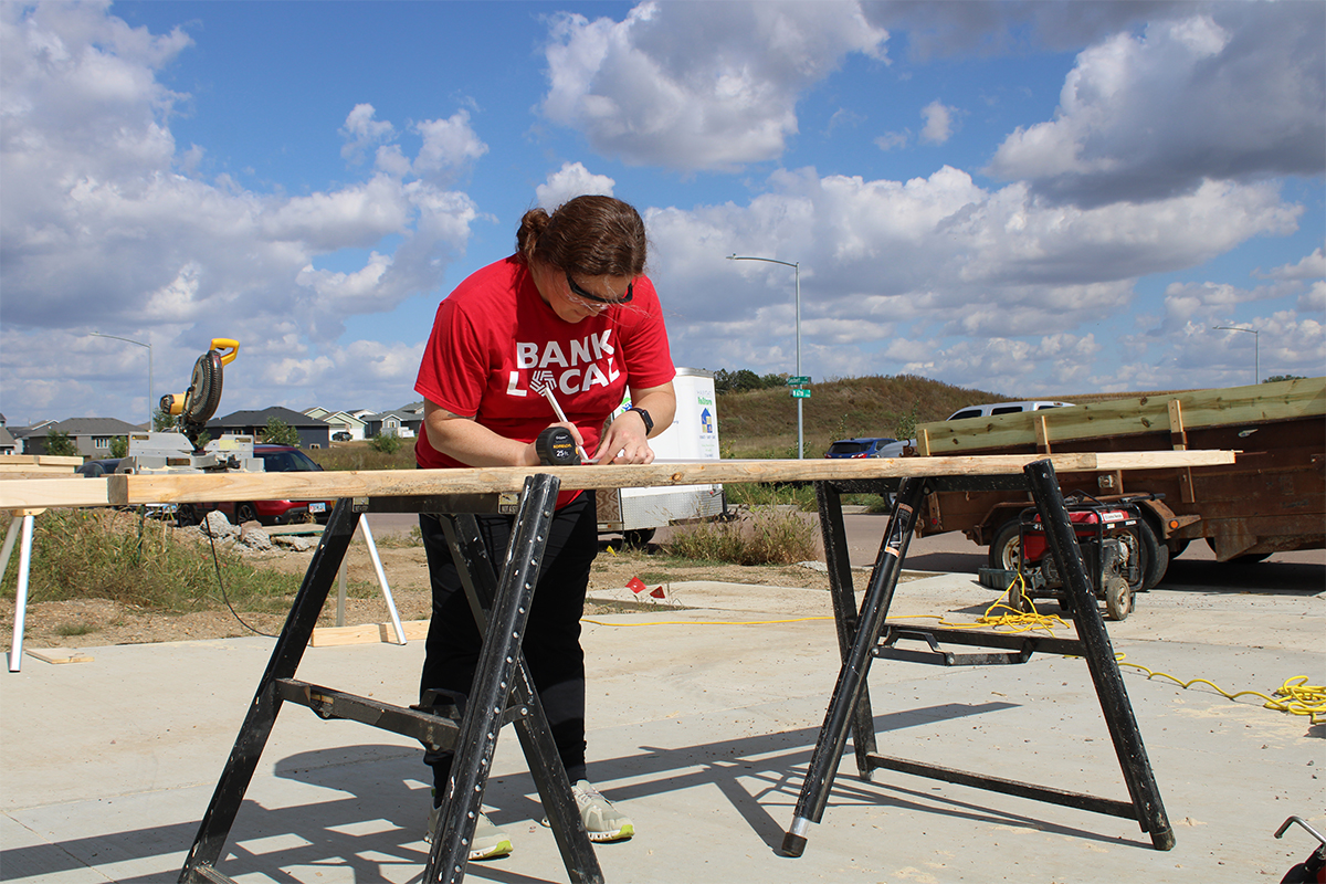 A woman measuring a wood board at Habitat for Humanity.