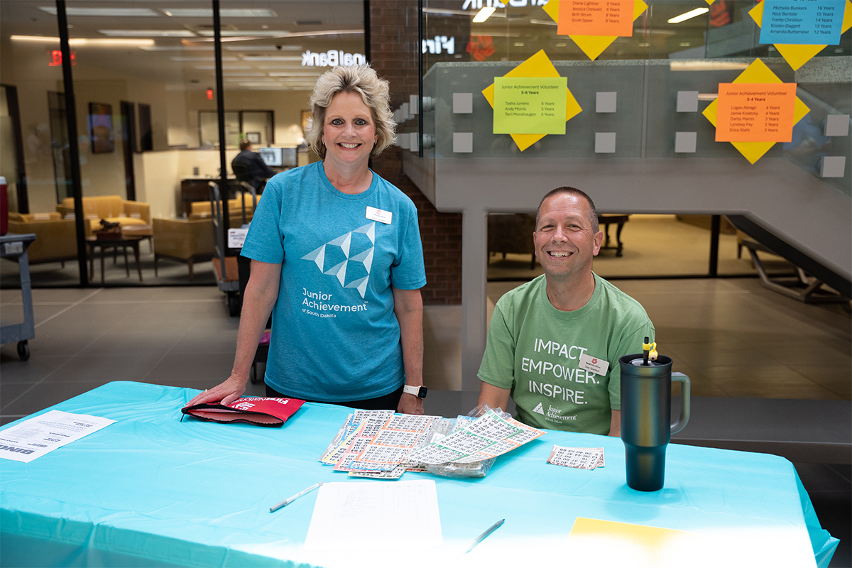 A woman and man selling bingo cards at a fundraiser.