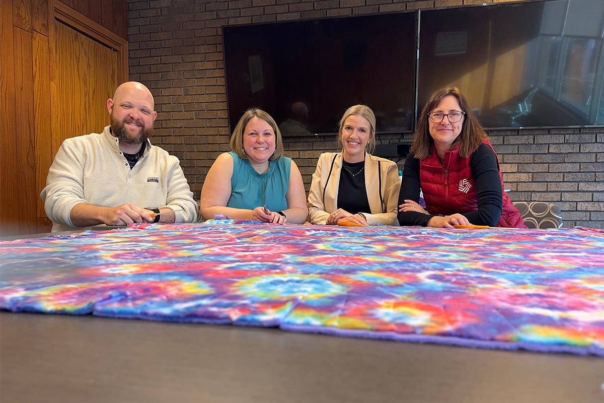 A group of people making a fleece tie blanket.