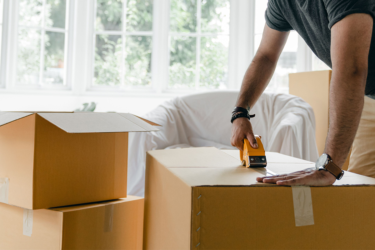 A person taping moving boxes in their living room.