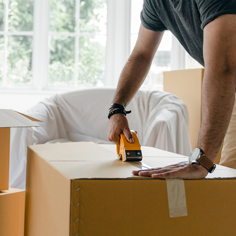 A person taping moving boxes in their living room.
